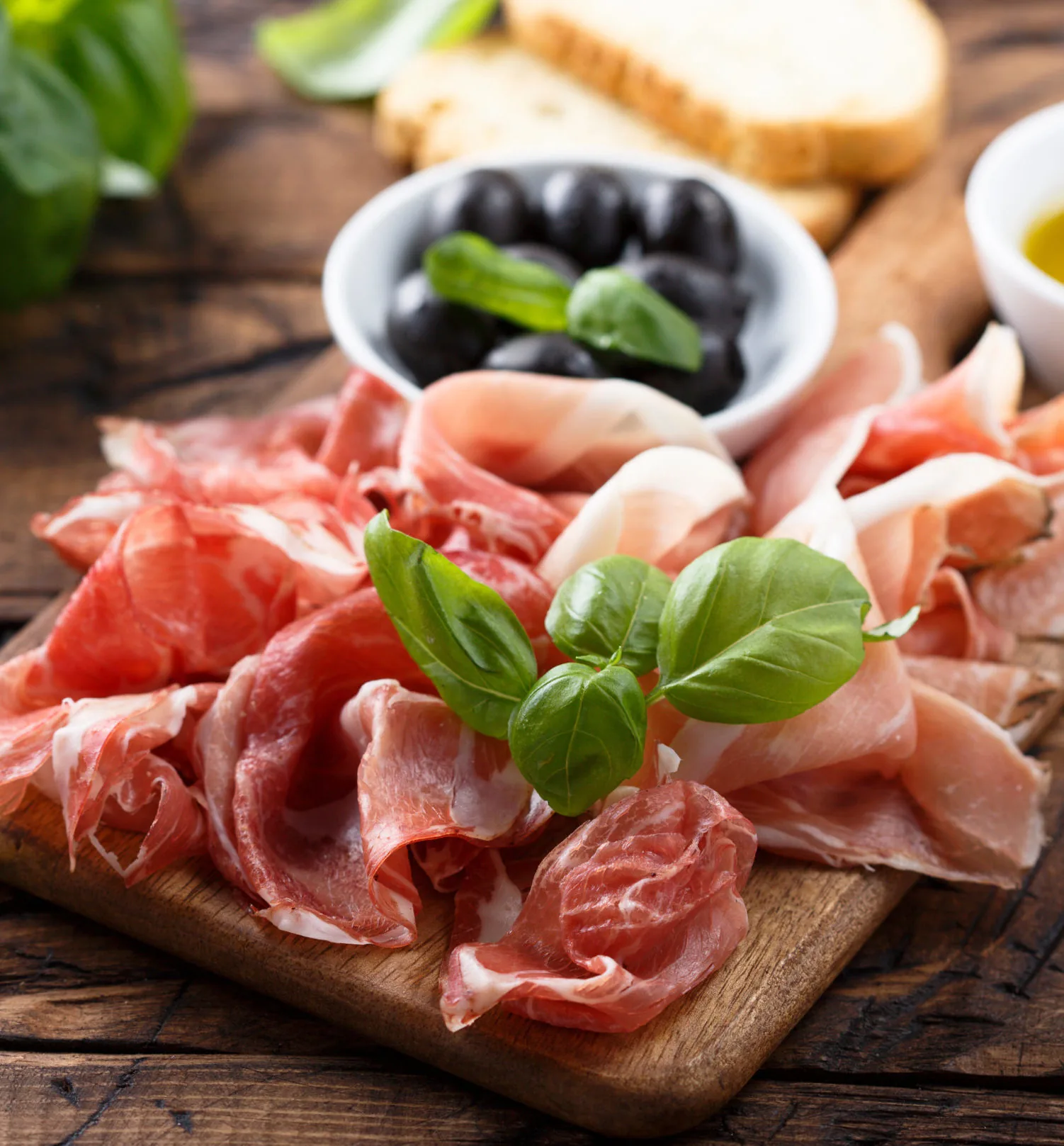 Spanische Tapas mit Serrano-Schinken, Oliven und Basilikum